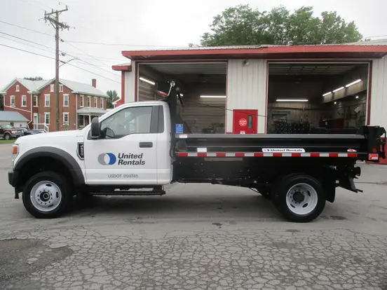 White Ford single-axle dump truck parked outside outside of a garage